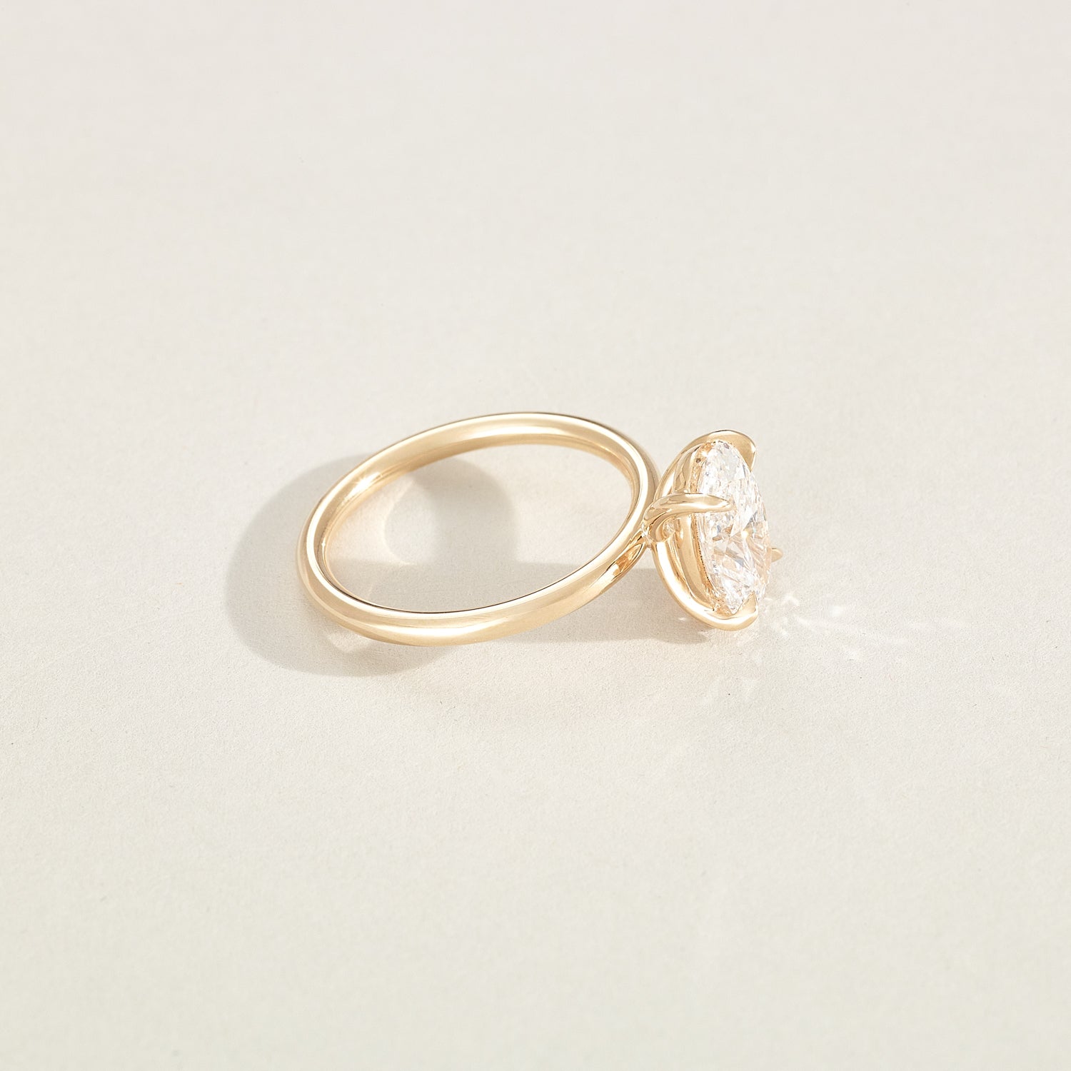 Gold ring with a diamond on a light beige background