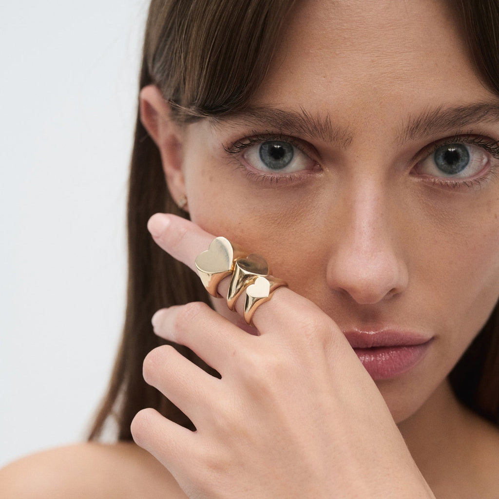 Woman showcases a set of luxurious gold rings, featuring unique shapes, on her fingers. Elegant and refined jewellery style.