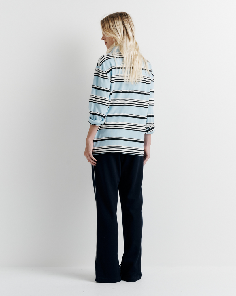 Model wearing the Varsity Polo – blue long sleeve polo shirt with classic collar and relaxed fit by ROMY.