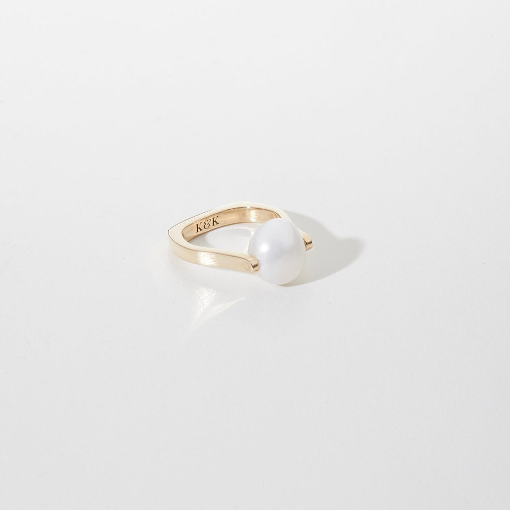 Gold ring with a pearl on a light gray background