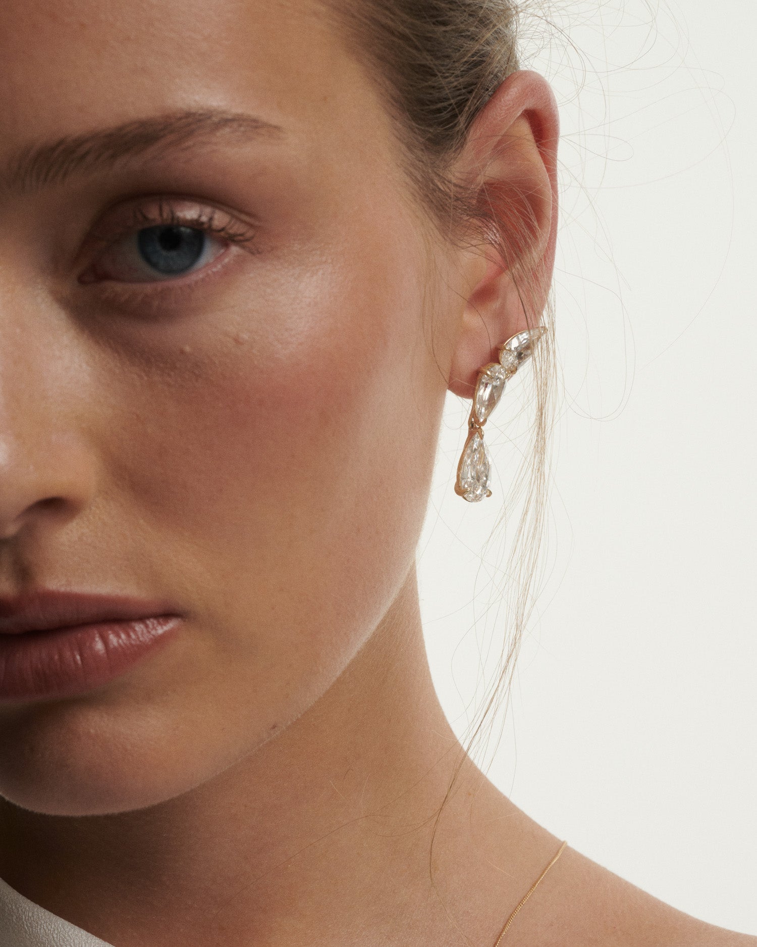 Close-up of a woman wearing a sparkling earring against a neutral background
[text overlay: Andrea wears the Nouve Drops and Studs]