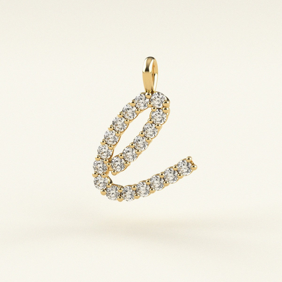 Gold 'E' pendant with diamonds on a beige background
