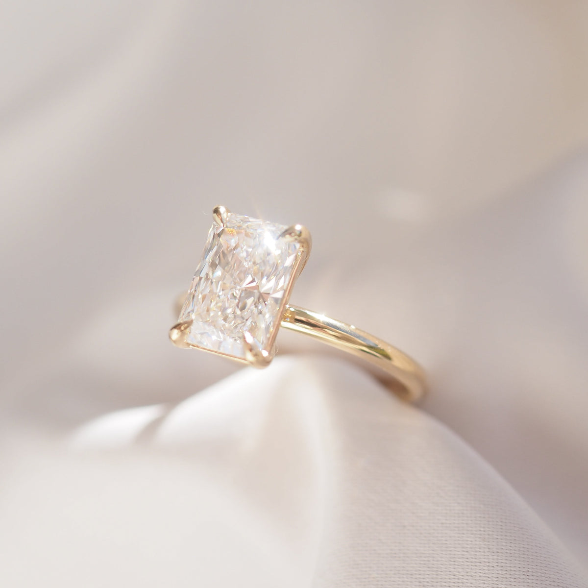 Gold ring with a large diamond on a soft white background